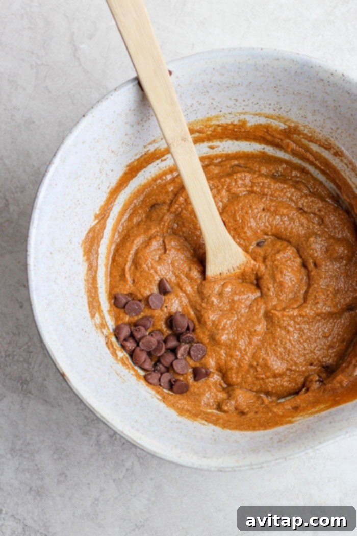 It’s pumpkin season! Which means it’s time to make this moist and flavorful Healthy Pumpkin Bread. Packed with pumpkin puree and a few chocolate chips + the just right amount of cinnamon, nutmeg, cloves and ginger, this pumpkin bread is something your whole family will enjoy! A close-up shot of the raw batter for healthy pumpkin bread, with visible pumpkin puree, chocolate chips, and spices, ready for baking.