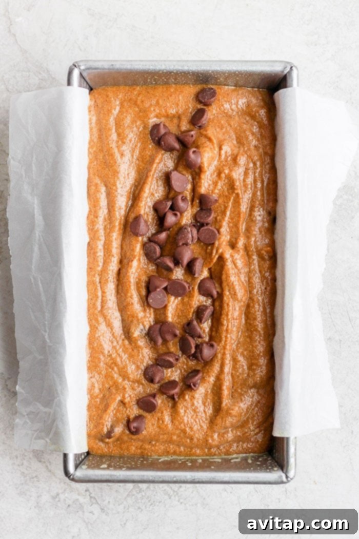 It’s pumpkin season! Which means it’s time to make this moist and flavorful Healthy Pumpkin Bread. Packed with pumpkin puree and a few chocolate chips + the just right amount of cinnamon, nutmeg, cloves and ginger, this pumpkin bread is something your whole family will enjoy! Healthy pumpkin bread batter in a loaf pan, topped with chocolate chips and ready to be baked to golden perfection.