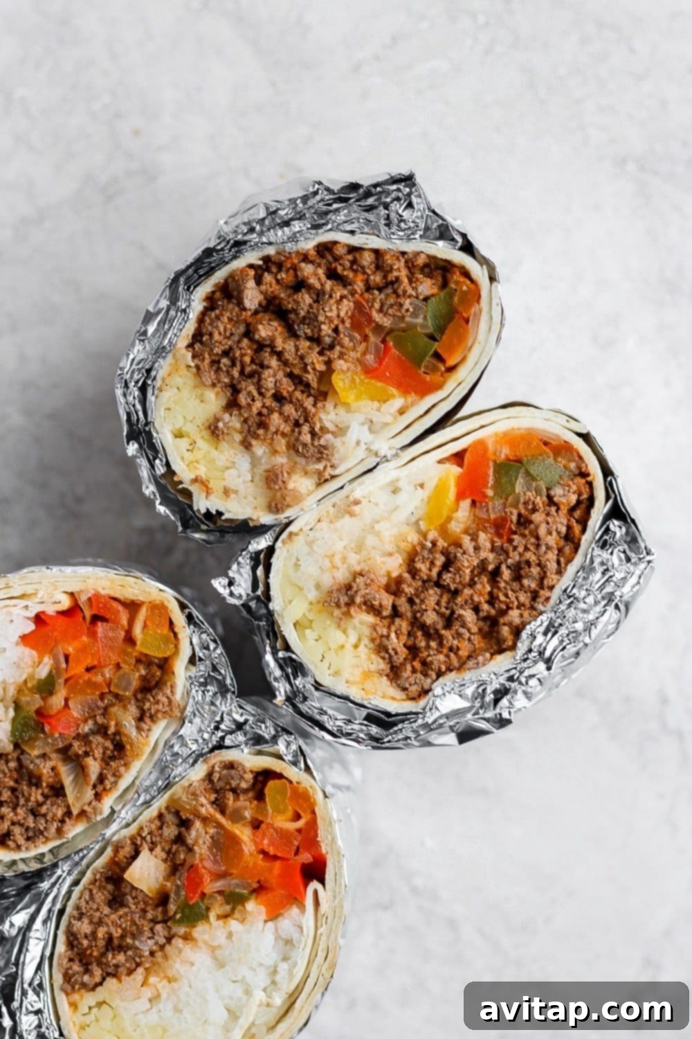 Freshly prepared ingredients for make-ahead burritos: roasted vegetables, ground beef, and cooked rice.