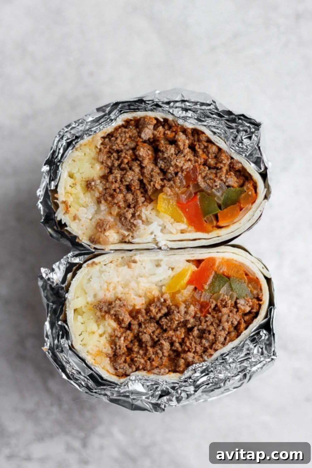 Multiple frozen burritos tightly wrapped in aluminum foil, ready for freezer storage.