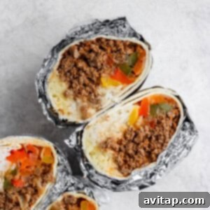 Three frozen burritos wrapped in foil with meat and vegetables.