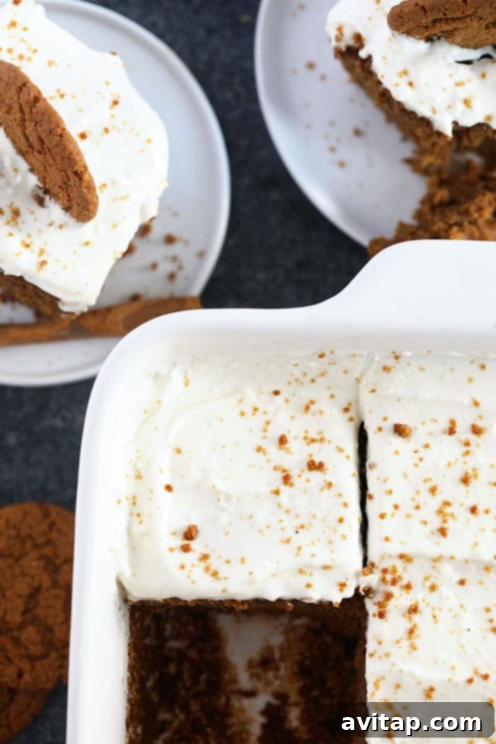 Multiple slices of classic gingerbread, generously frosted with lightened-up cream cheese frosting and garnished with ground cinnamon and crushed gingersnap cookies, artfully arranged on a serving plate.