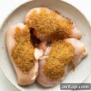 Seasoned chicken breasts on a white plate.