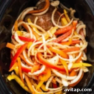 A crock pot filled with peppers and onions.