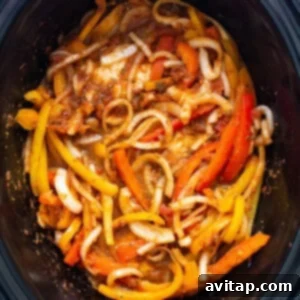 A slow cooker filled with peppers and onions.