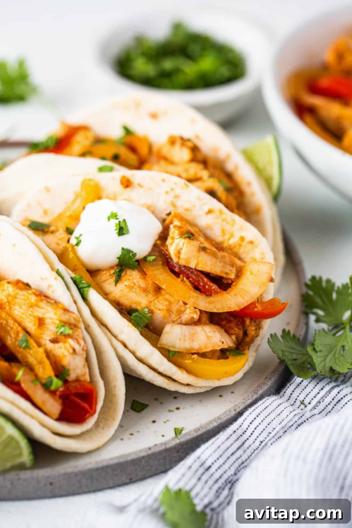Chicken tacos with peppers and sour cream on a plate.