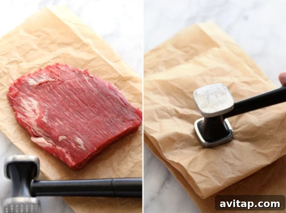 Hands tenderizing flank steak with a meat mallet, protected by parchment paper, for a beef casserole