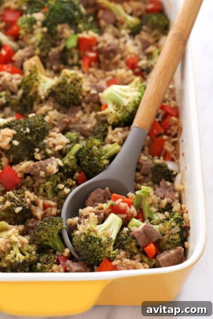 Serving of Beef and Broccoli Casserole with rice in a white rectangular dish, garnished with fresh herbs