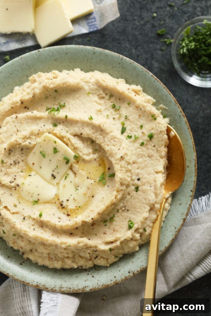Cauliflower mashed potatoes in a bowl, garnished with herbs and a pat of butter, ready to serve.
