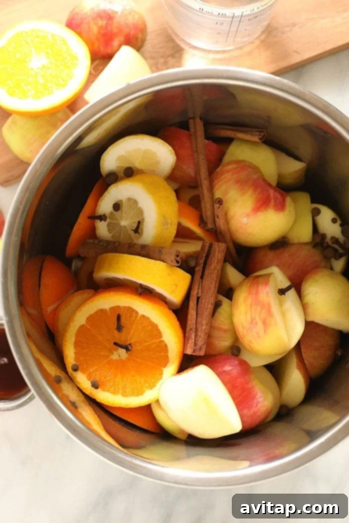 Instant Pot Apple Cider Ingredients Fresh apple cider ingredients including sliced apples, oranges, lemons, and whole spices, placed in an Instant Pot before cooking.
