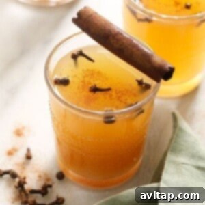 Easy Instant Pot Apple Cider 2 Two glasses of Instant Pot apple cider garnished with cinnamon sticks and fresh apples.