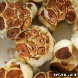 A small bowl filled with perfectly roasted garlic cloves, golden-brown and tender, fresh out of the oven.