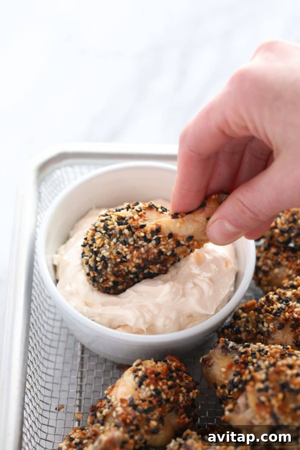 Everything Bagel Seasoning Wings with Cream Cheese Dip (Keto!) Crispy Everything Bagel chicken wing being dipped into a creamy white sauce.