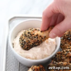 a person dipping crispy baked chicken wings in a bowl.