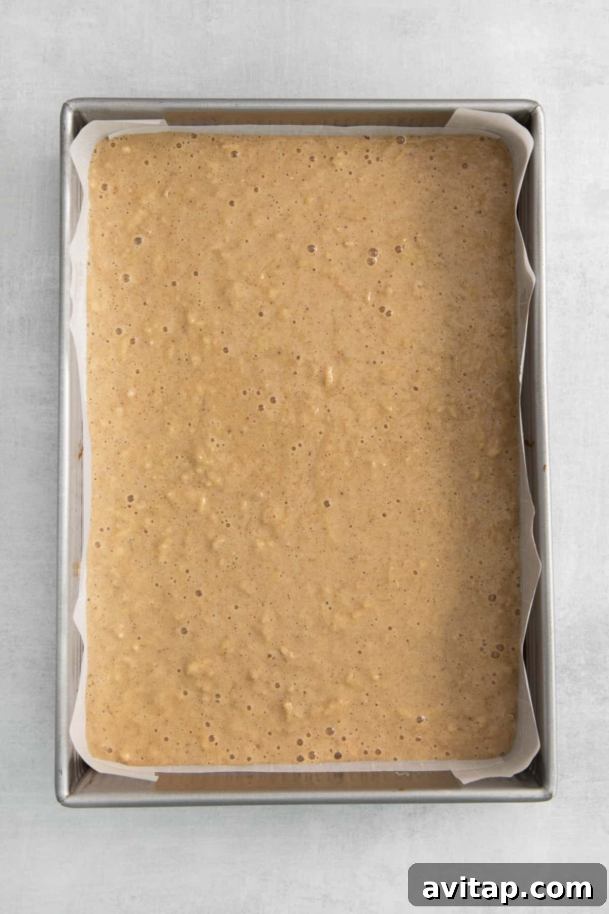 Apple cake batter in a parchment-lined baking pan.