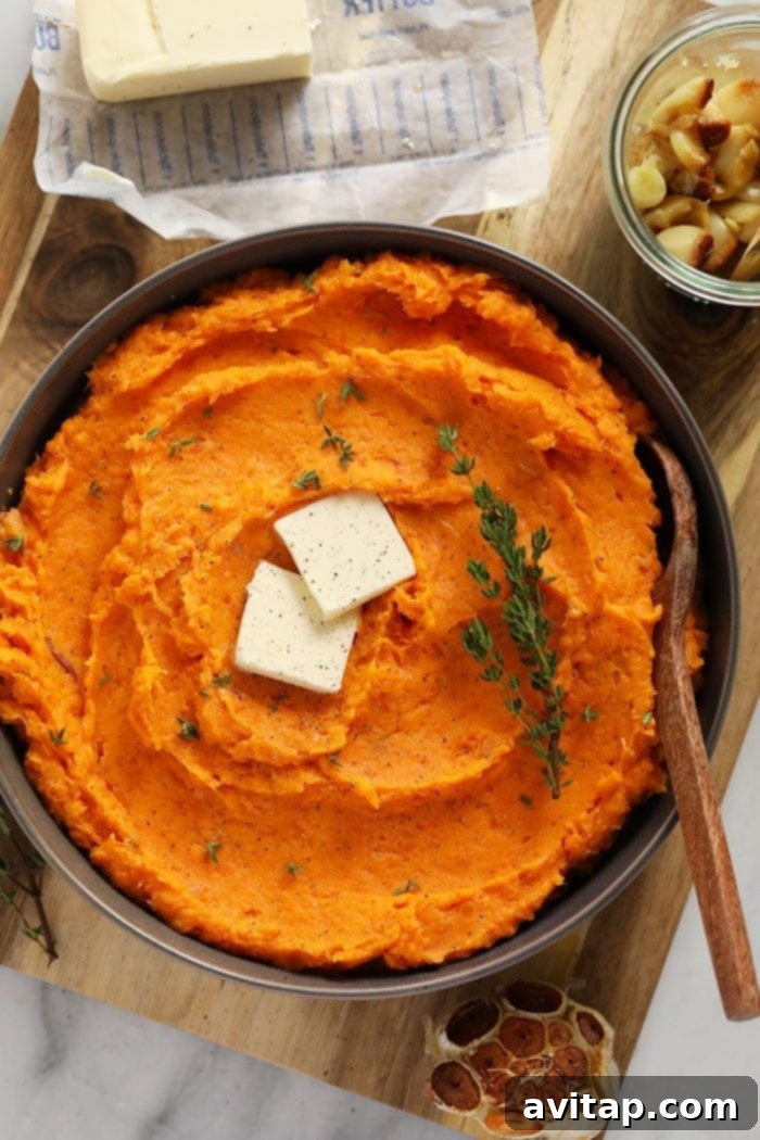 Velvety Sweet Potato Mash 2 A vibrant bowl of healthy mashed sweet potatoes, garnished with a dollop of melted butter and fresh thyme leaves, ready to be served.