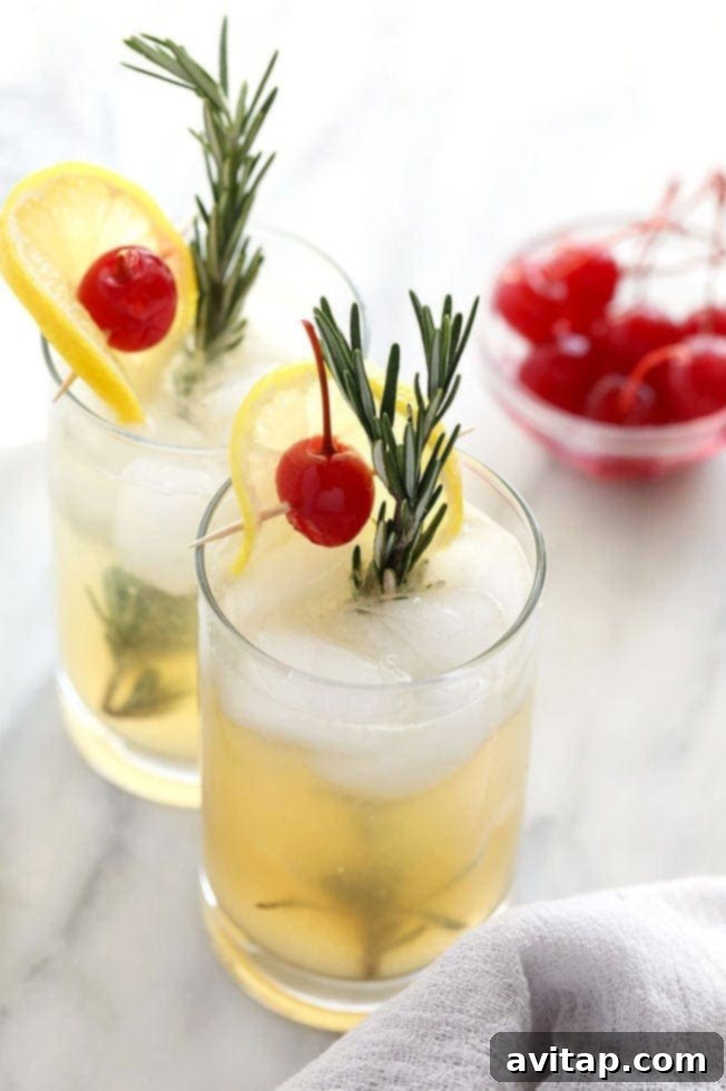 A Rosemary Vodka Collins cocktail in a tall glass, garnished with a sprig of fresh rosemary and a lemon slice.