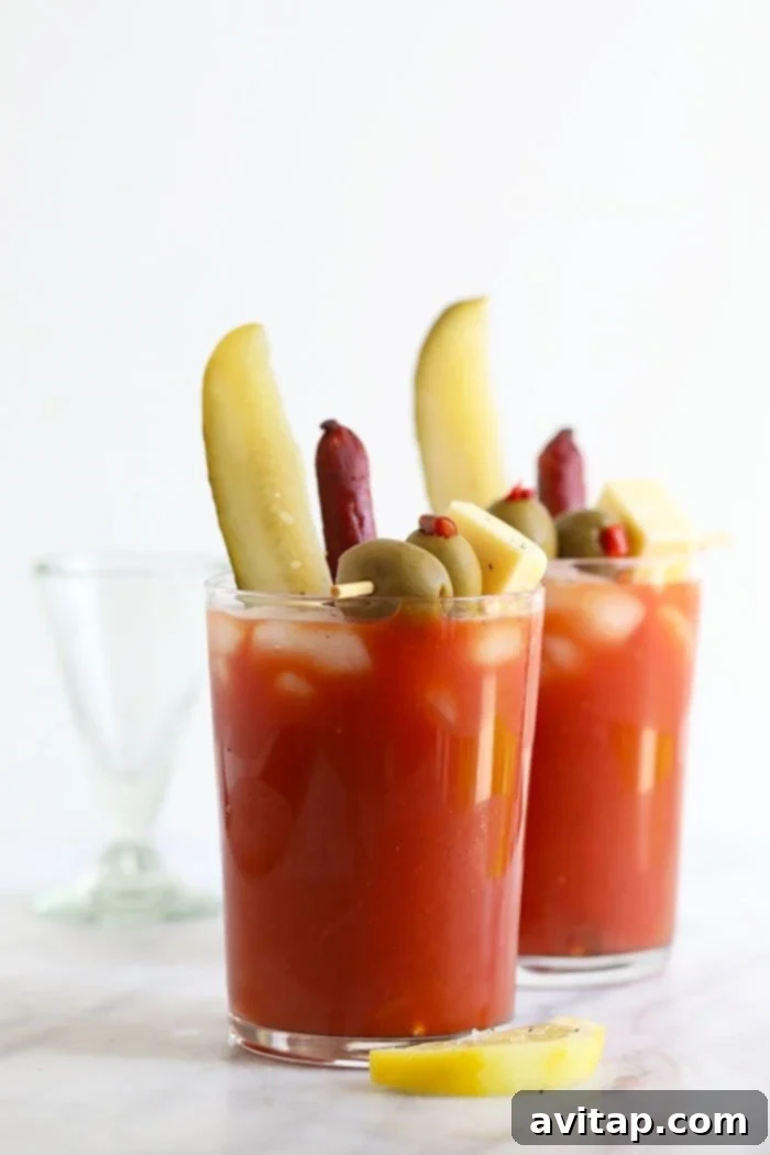 A Bloody Mary cocktail in a glass, lavishly garnished with pickles, olives, and cheese for brunch.