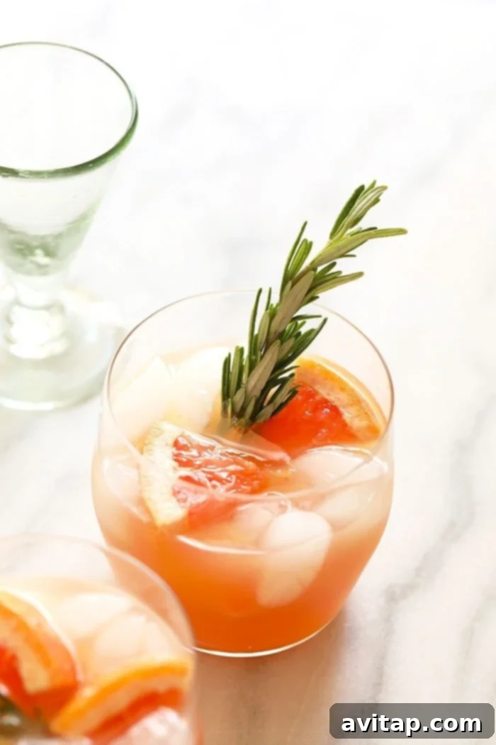 A Honey Greyhound Cocktail in a glass, garnished with a grapefruit slice and a sprig of thyme.