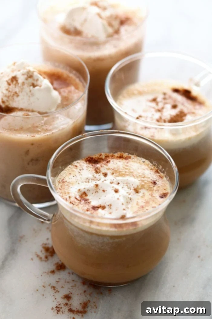 An almond milk chai tea latte served in a clear glass mug, topped with frothed milk and a sprinkle of cinnamon.