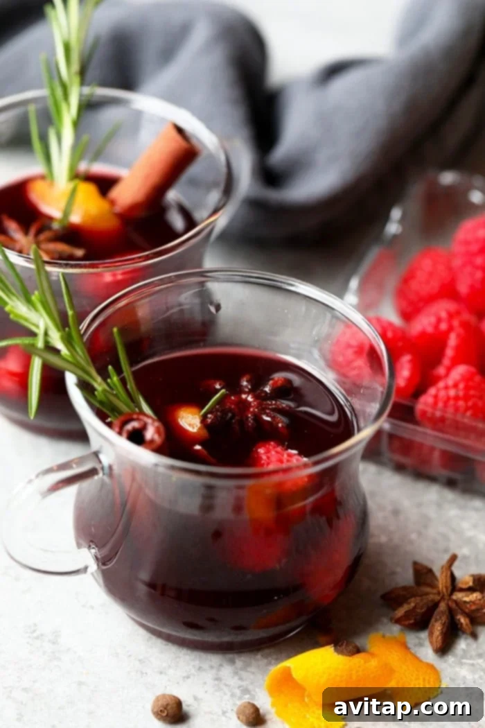 A mug of festive mulled wine, garnished with rosemary and cranberries, against a cozy backdrop.
