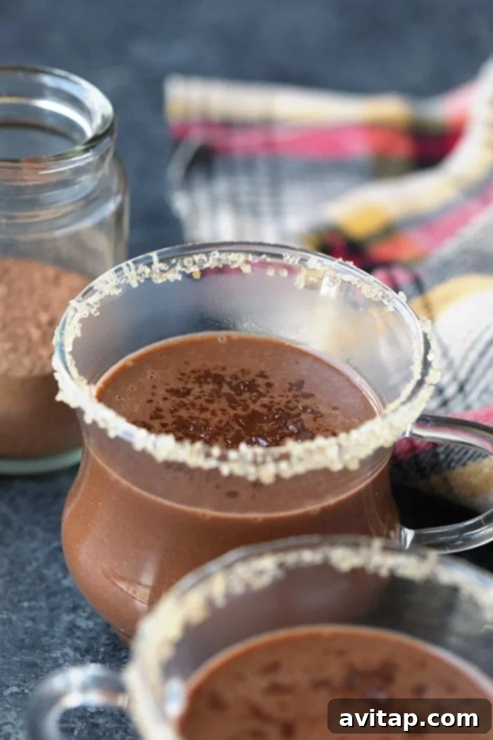A mug of decadent spiced coconut hot chocolate, topped with whipped coconut cream and cinnamon.