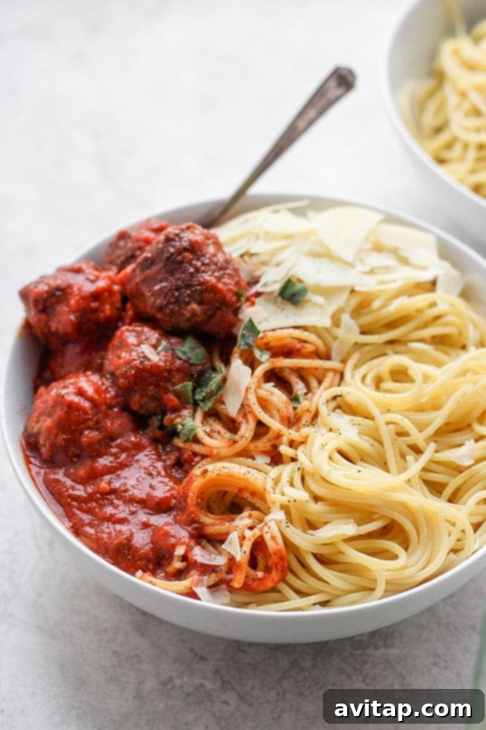 An Italian meatball recipe the whole family will adore, made with ground beef, Italian breadcrumbs, and Parmesan cheese. A generous bowl of spaghetti and meatballs, garnished with fresh herbs and Parmesan cheese.