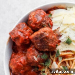 Italian meatballs in a bowl with grated parmesan cheese on top.