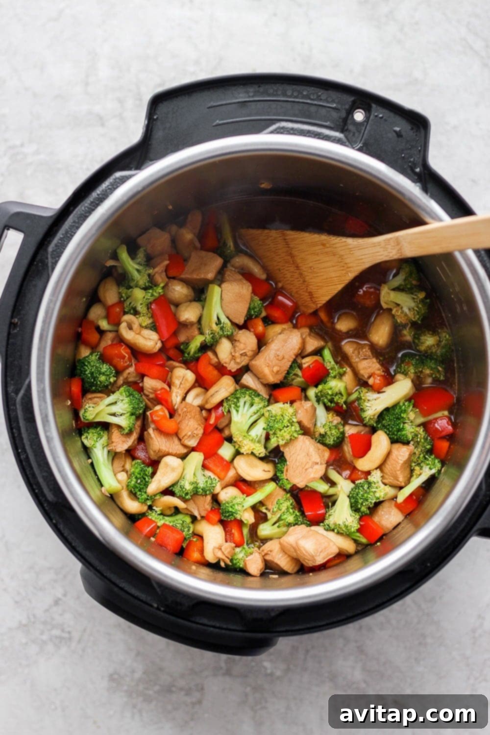 Instant Pot Cashew Chicken actively cooking in the pot, showing the sauce thickening and vegetables steaming