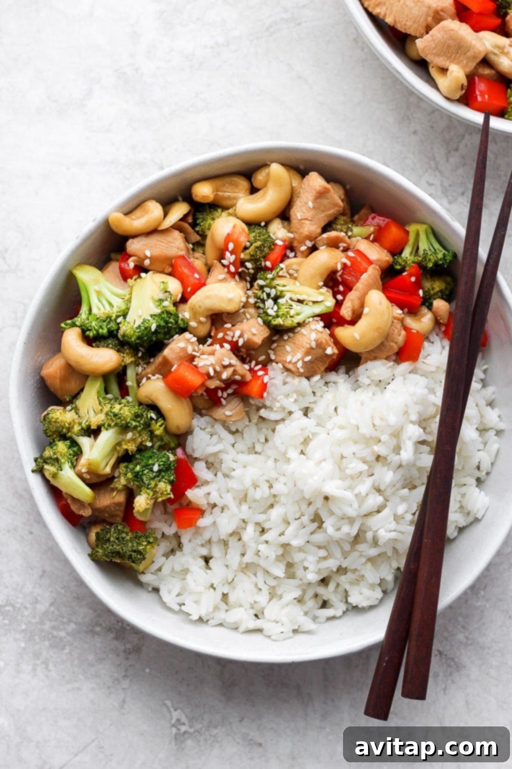 A close-up of the finished Instant Pot Cashew Chicken Stir Fry in a bowl, garnished and ready to be enjoyed with chopsticks