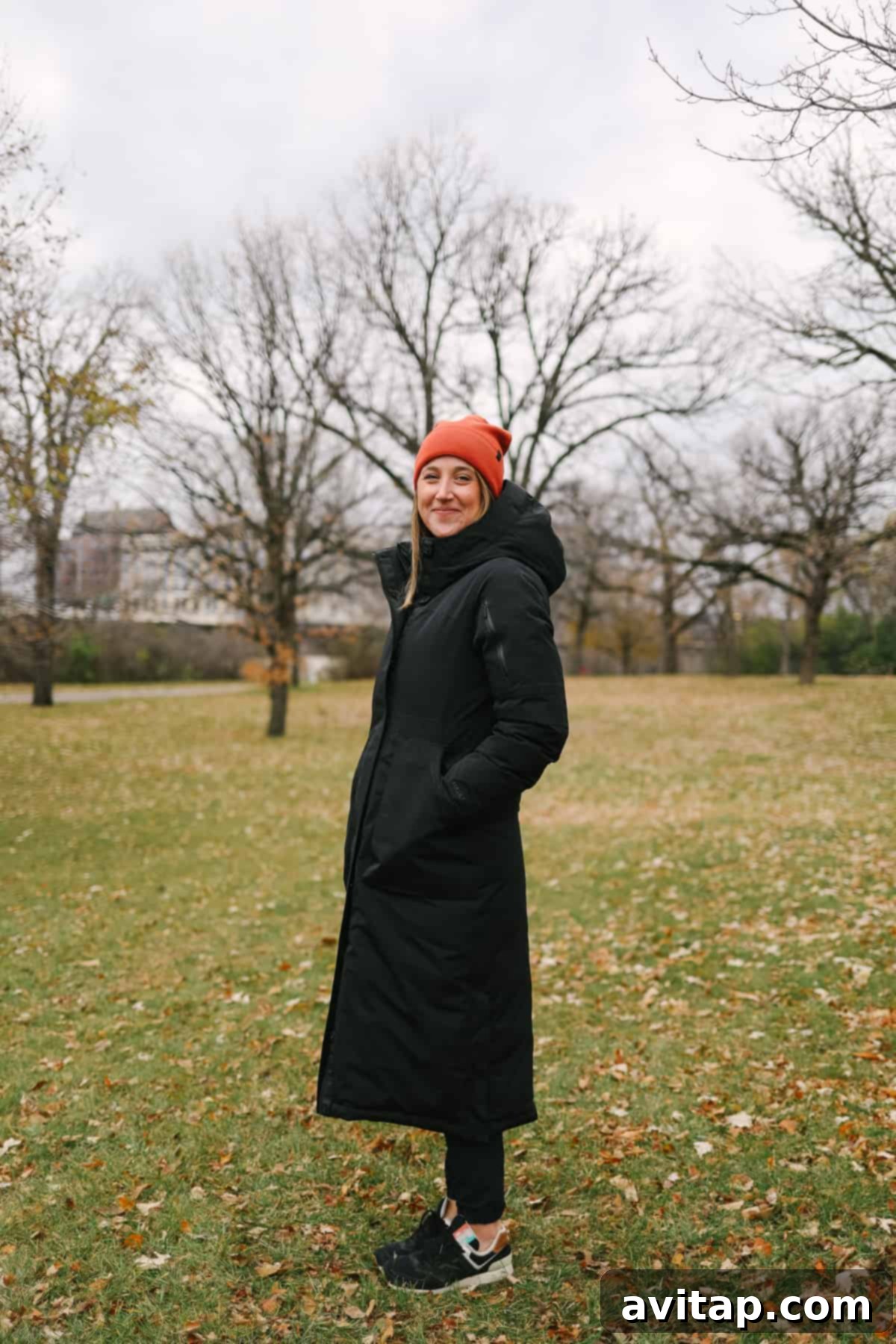 A woman smiling warmly, dressed in a long, elegant Lululemon Snow Warrior Long Parka.