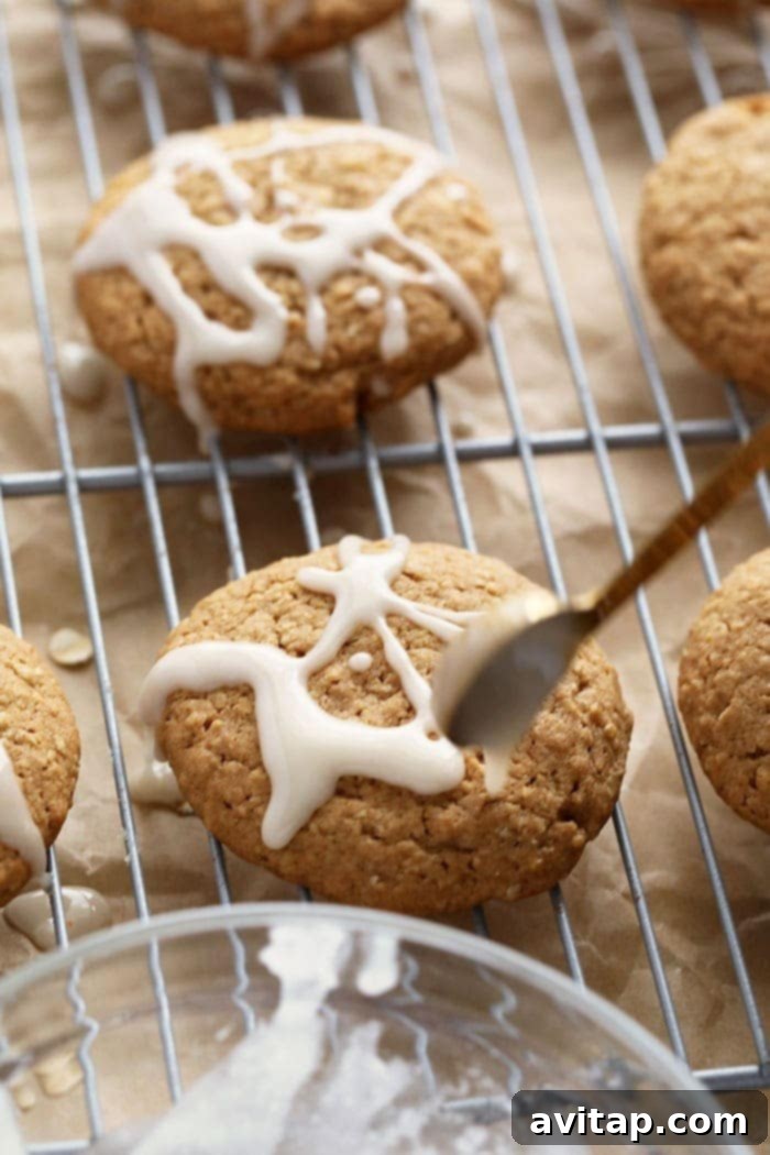 The Art of Drizzling Easy Homemade Icing on Oatmeal Cookies A freshly baked oatmeal cookie being drizzled with homemade white icing on a cooling rack
