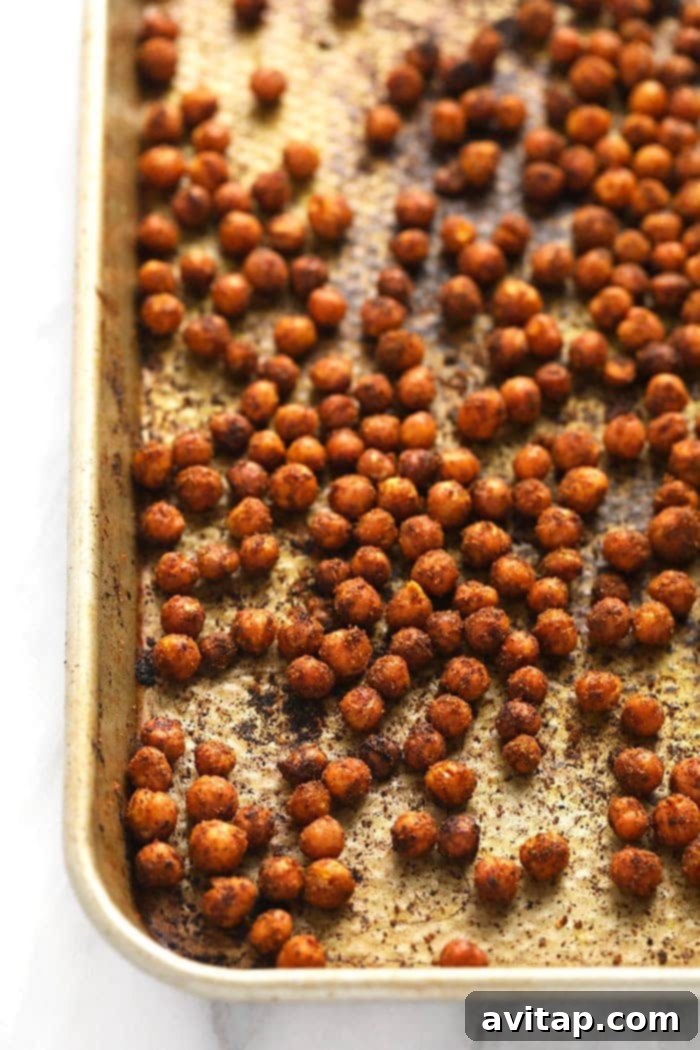 Crispy, spiced chickpeas spread out evenly on a baking pan, ready for roasting.