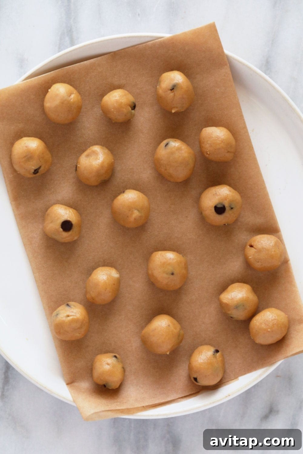 Small, perfectly rolled edible cookie dough bites on a plate, ready for freezing.