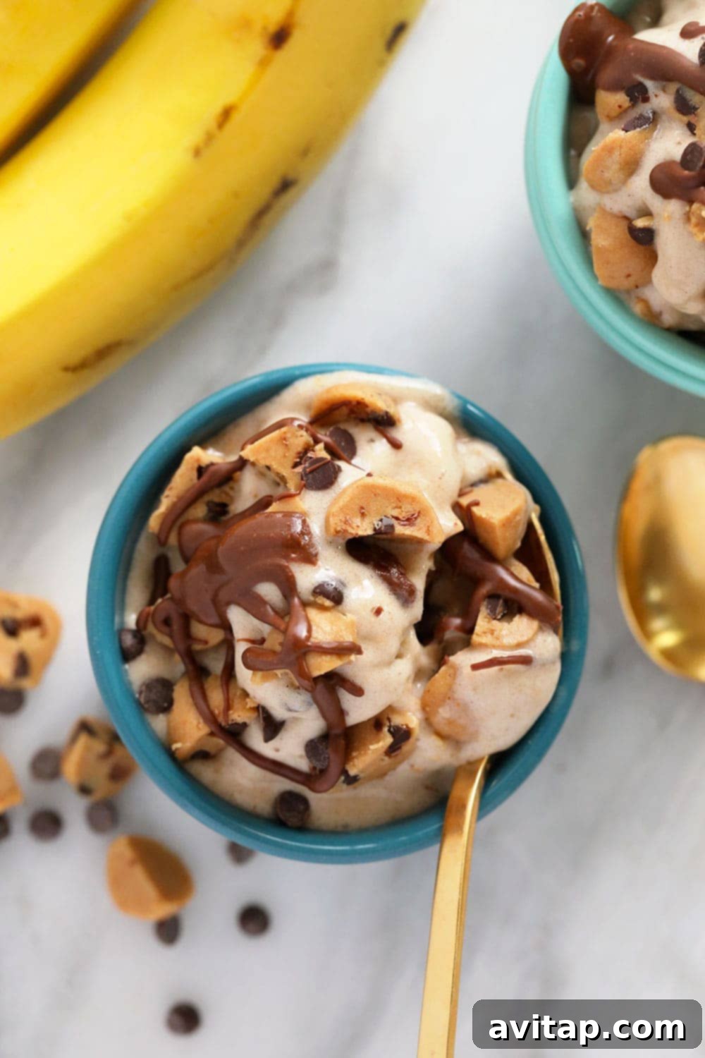 A beautiful bowl of vegan cookie dough banana nice cream, garnished with extra cookie dough pieces and chocolate sauce.
