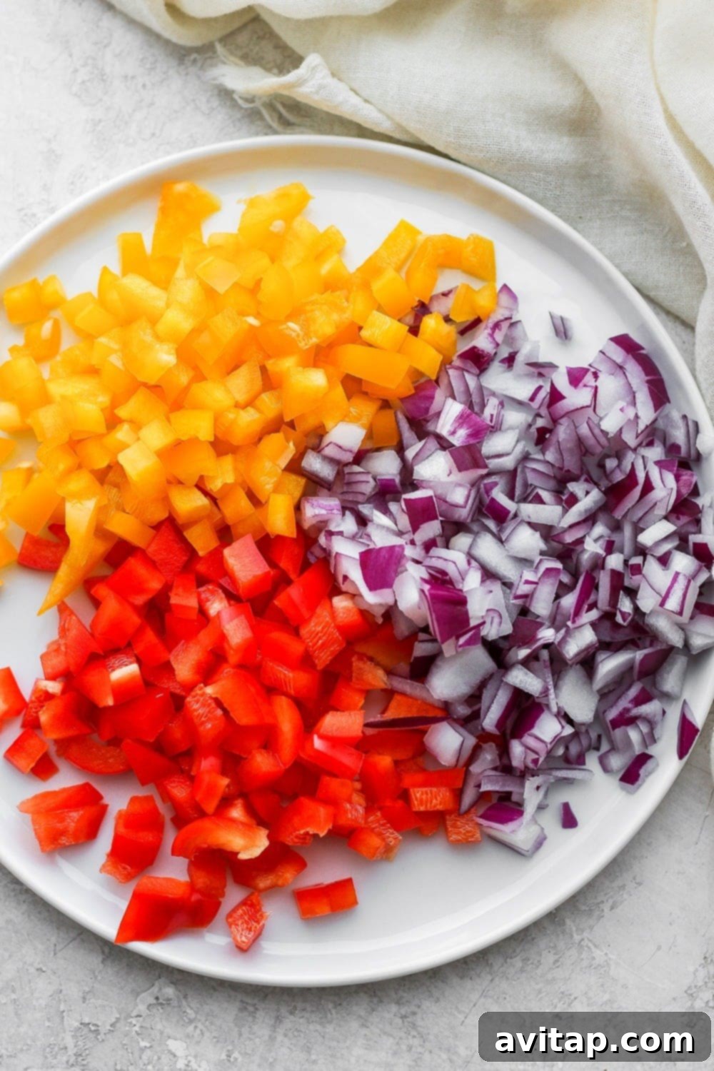 Freshly chopped bell peppers and red onion on a white plate