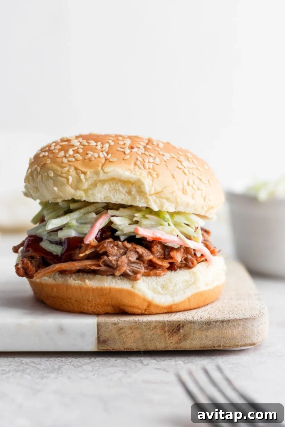 Pulled pork on a bun with slaw, showcasing its tenderness and juiciness.
