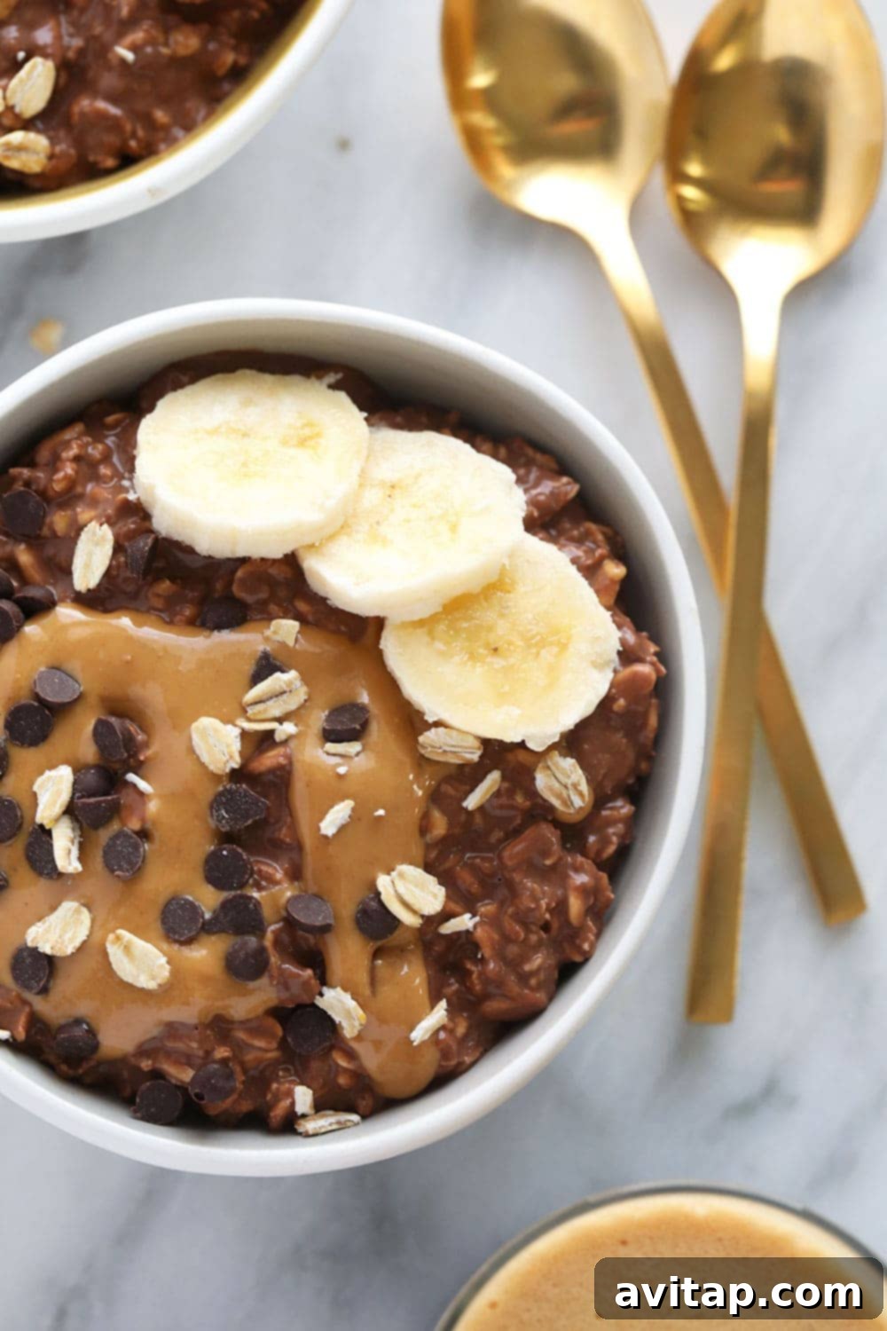 Chocolate Peanut Butter Overnight Oats Topped A beautifully prepared bowl of Chocolate Peanut Butter Overnight Oats, garnished with a generous drizzle of peanut butter and a sprinkle of mini chocolate chips.
