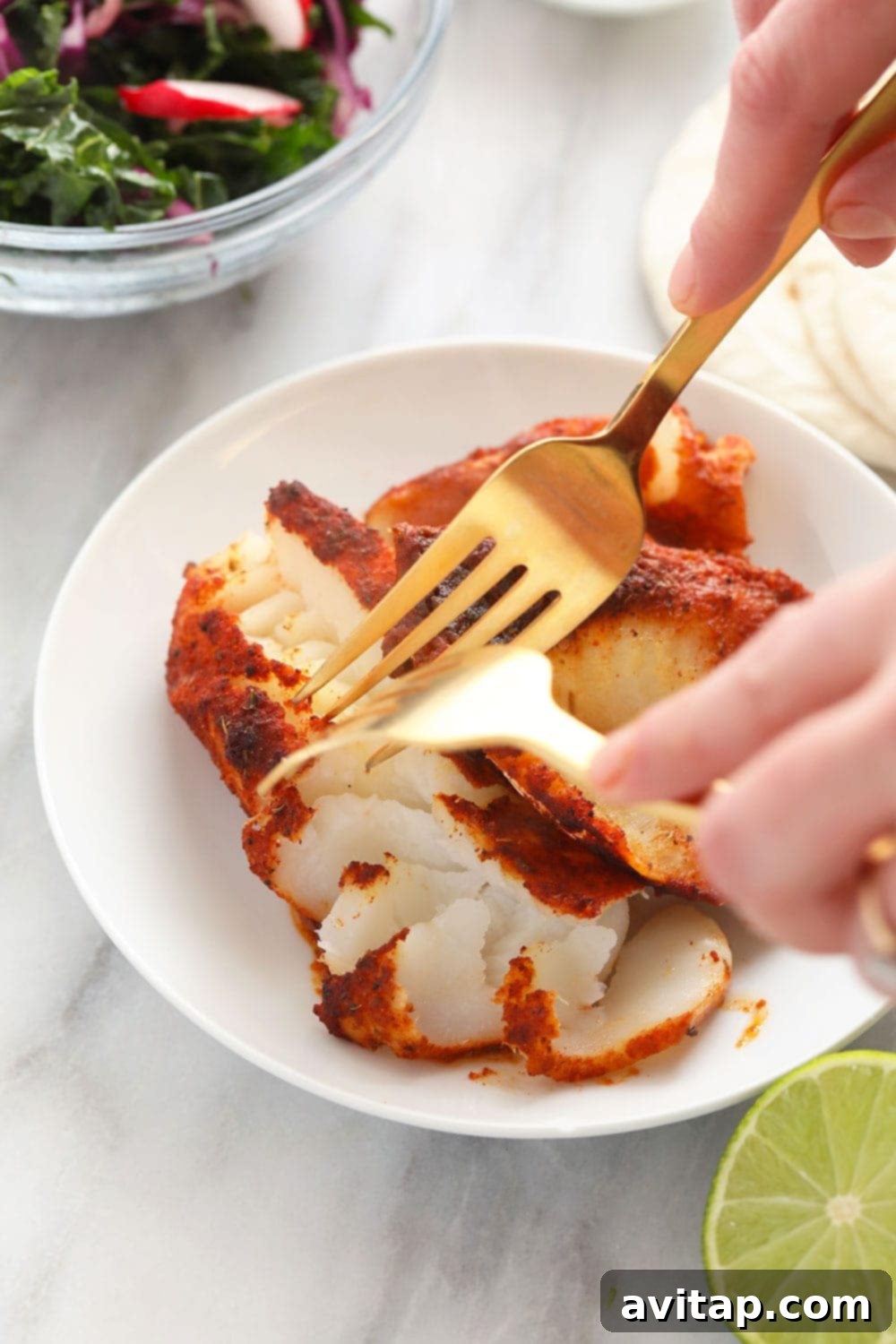Expertly chunking baked fish fillets in a pan, preparing them for delicious fish tacos.