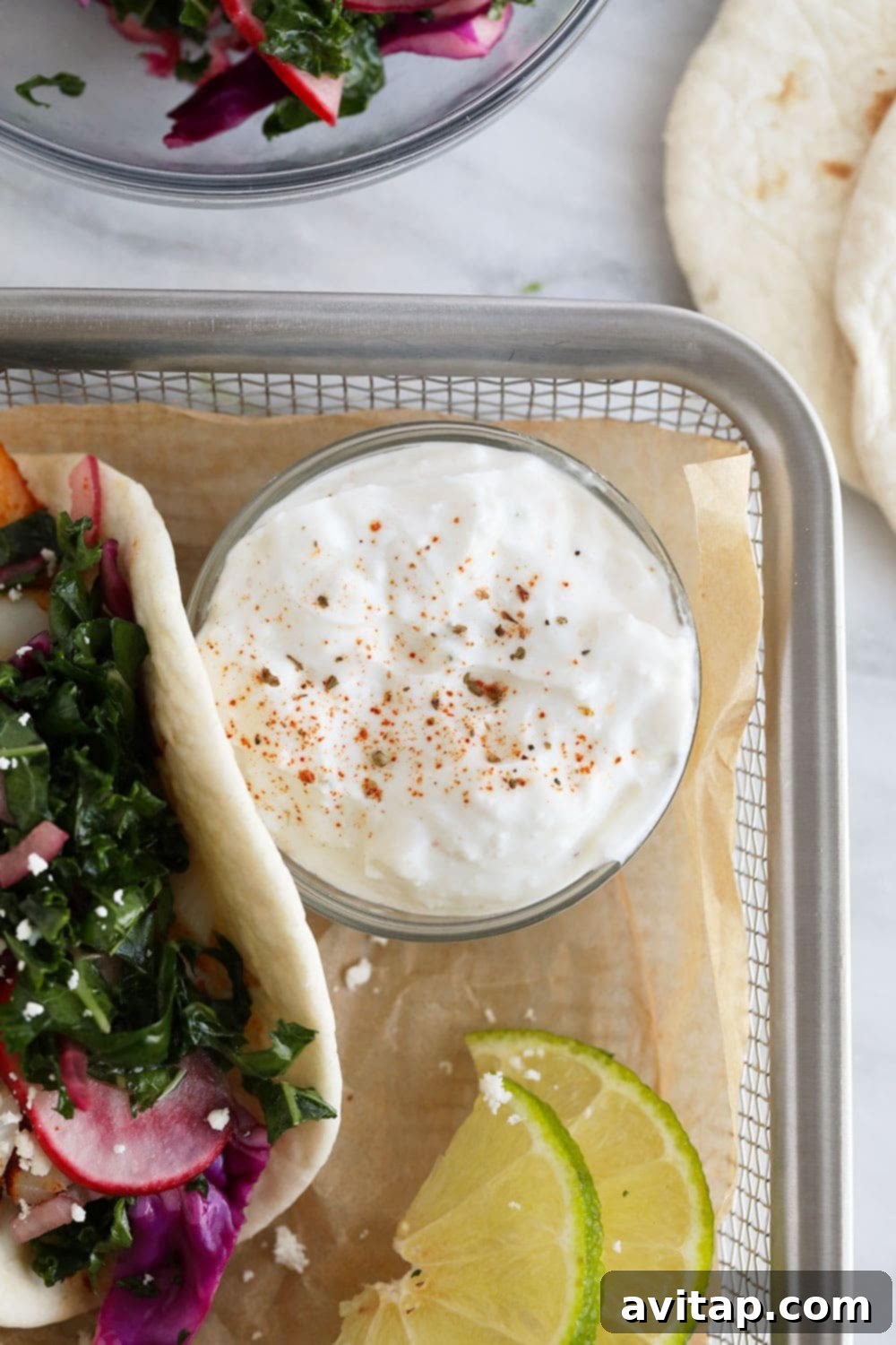 A vibrant bowl of fresh lime crema, perfect for drizzling over baked fish tacos.