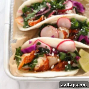 Three fish tacos with kale and radishes on a tray.