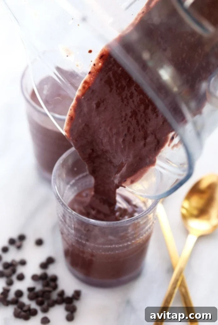 This chocolate protein shake is chocolatey, packed with protein, and the perfect post workout snack or easy breakfast recipe! Velvety blended chocolate protein shake being carefully poured into a tall glass
