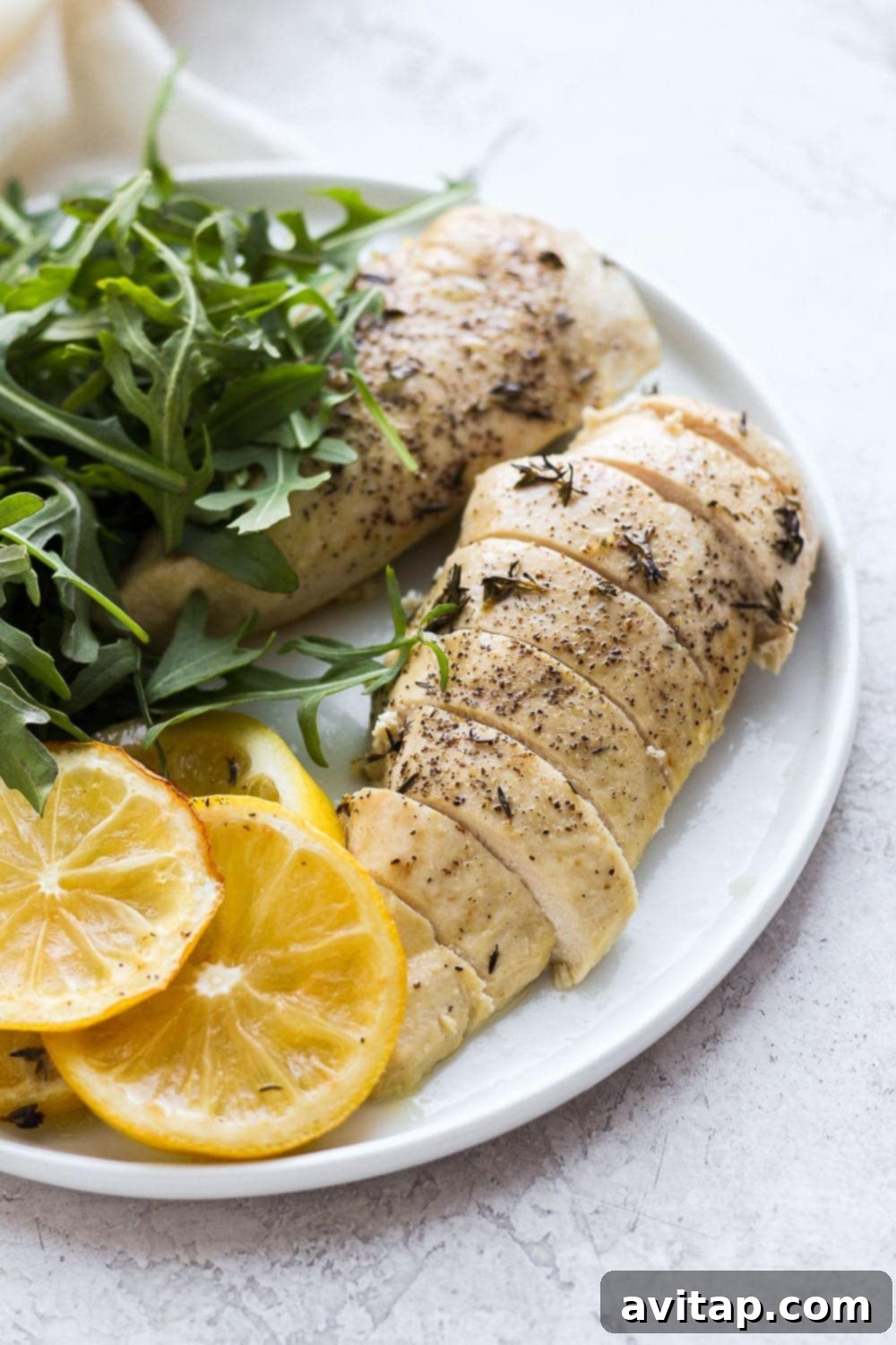 Enjoy tender, juicy baked lemon chicken – a delicious and healthy dinner option for busy weeknights. Perfectly sliced baked lemon chicken on a plate, ready to be served, garnished with fresh herbs.