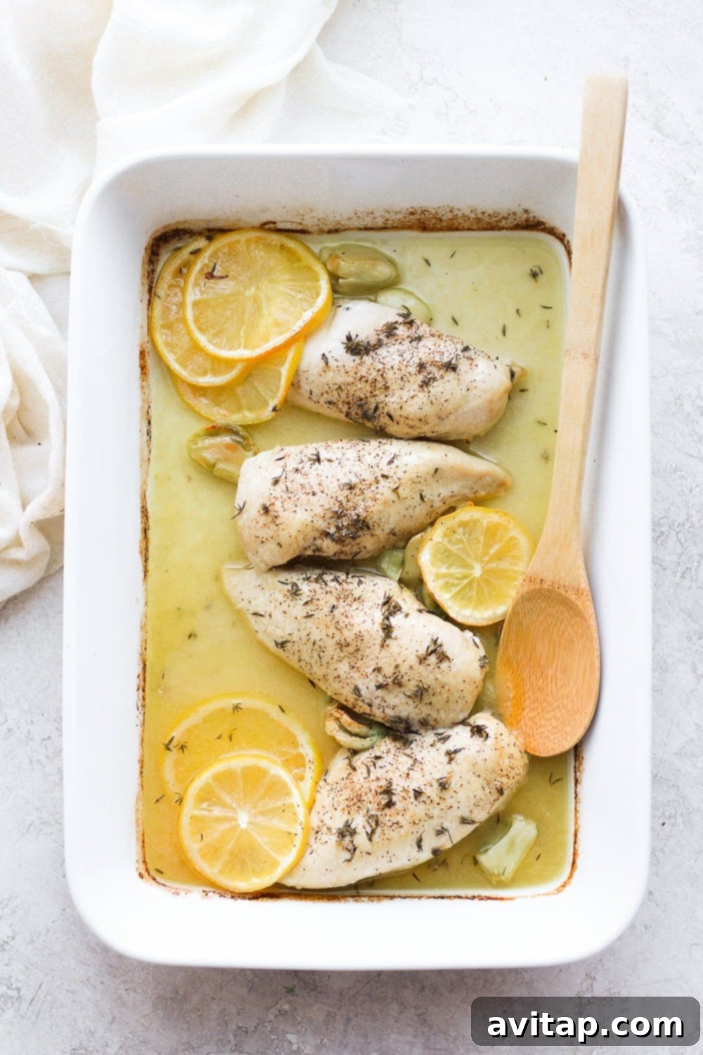 This baked lemon chicken is a flavorful, fresh meal ready in less than an hour, perfect for your weekly menu. Golden-brown baked lemon chicken breasts resting in a casserole dish after baking, glistening with sauce.