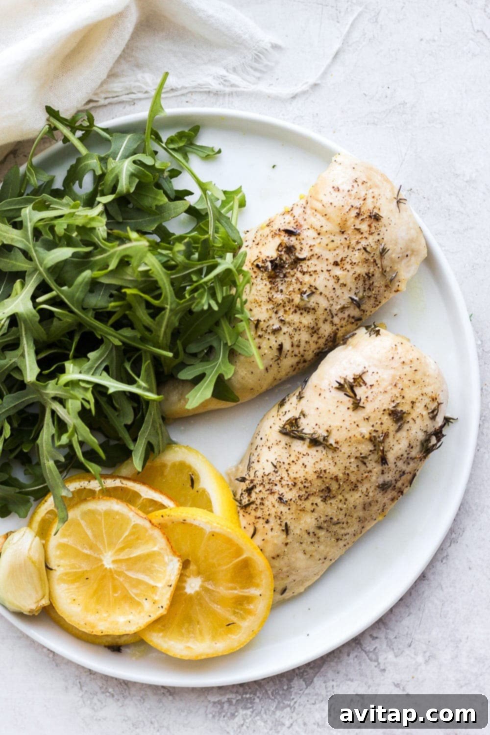 Serve this healthy baked lemon chicken alongside your favorite fresh salad for a complete meal. Succulent baked lemon chicken breast served on a white plate, garnished with fresh herbs and a lemon slice.