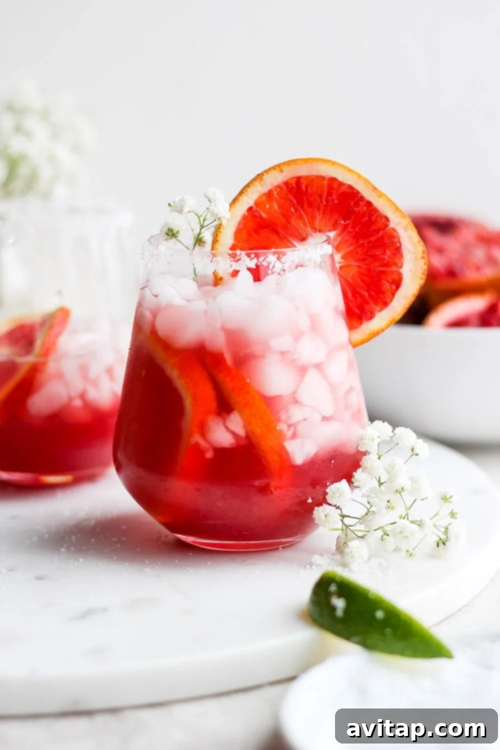 A vibrant blood orange margarita in a glass, garnished with a blood orange slice and a salt rim
