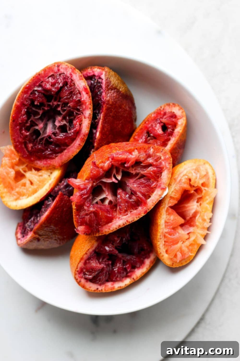 Freshly juiced blood oranges on a cutting board, ready for cocktail making
