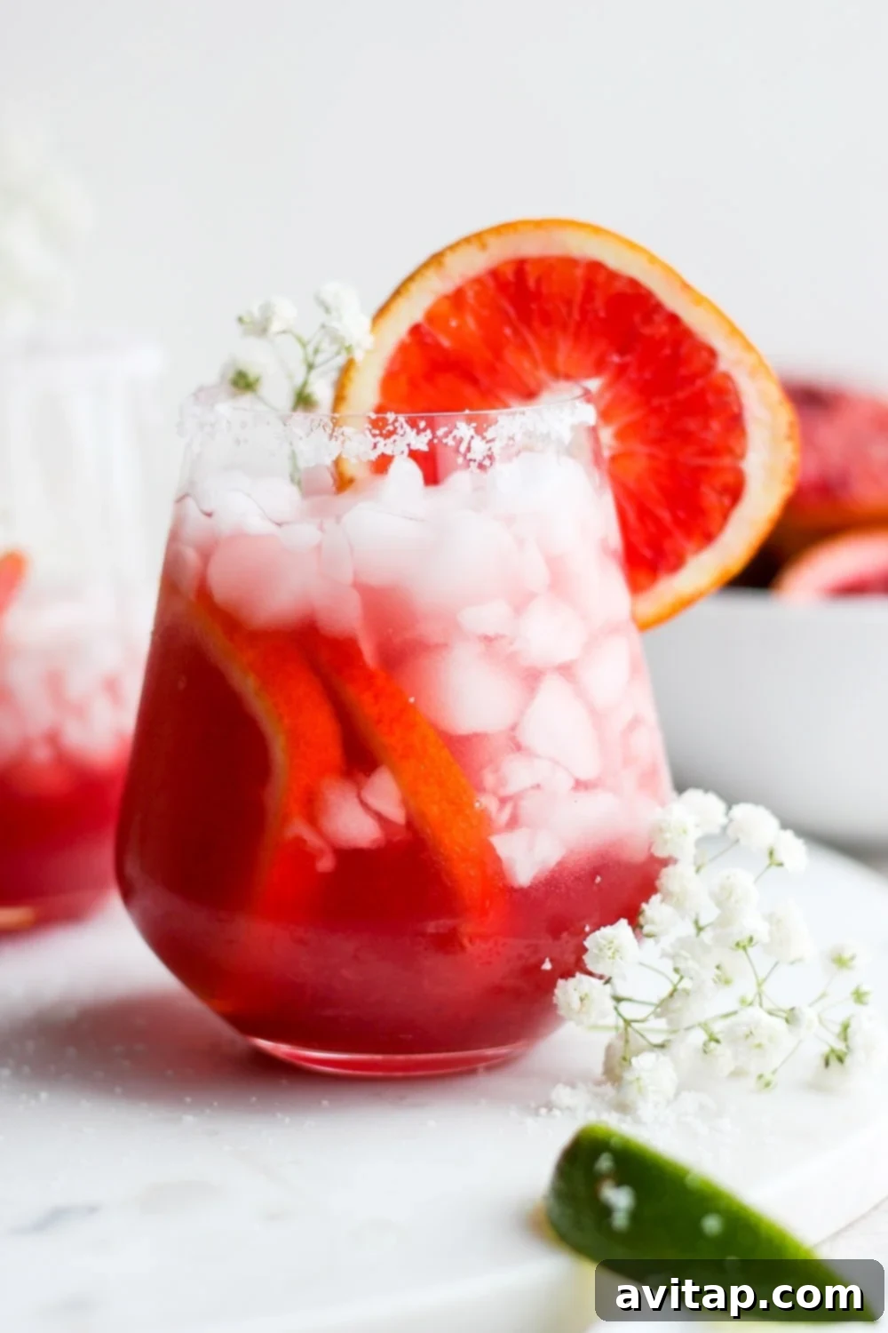Two blood orange margaritas in salt-rimmed glasses, garnished with blood orange slices.