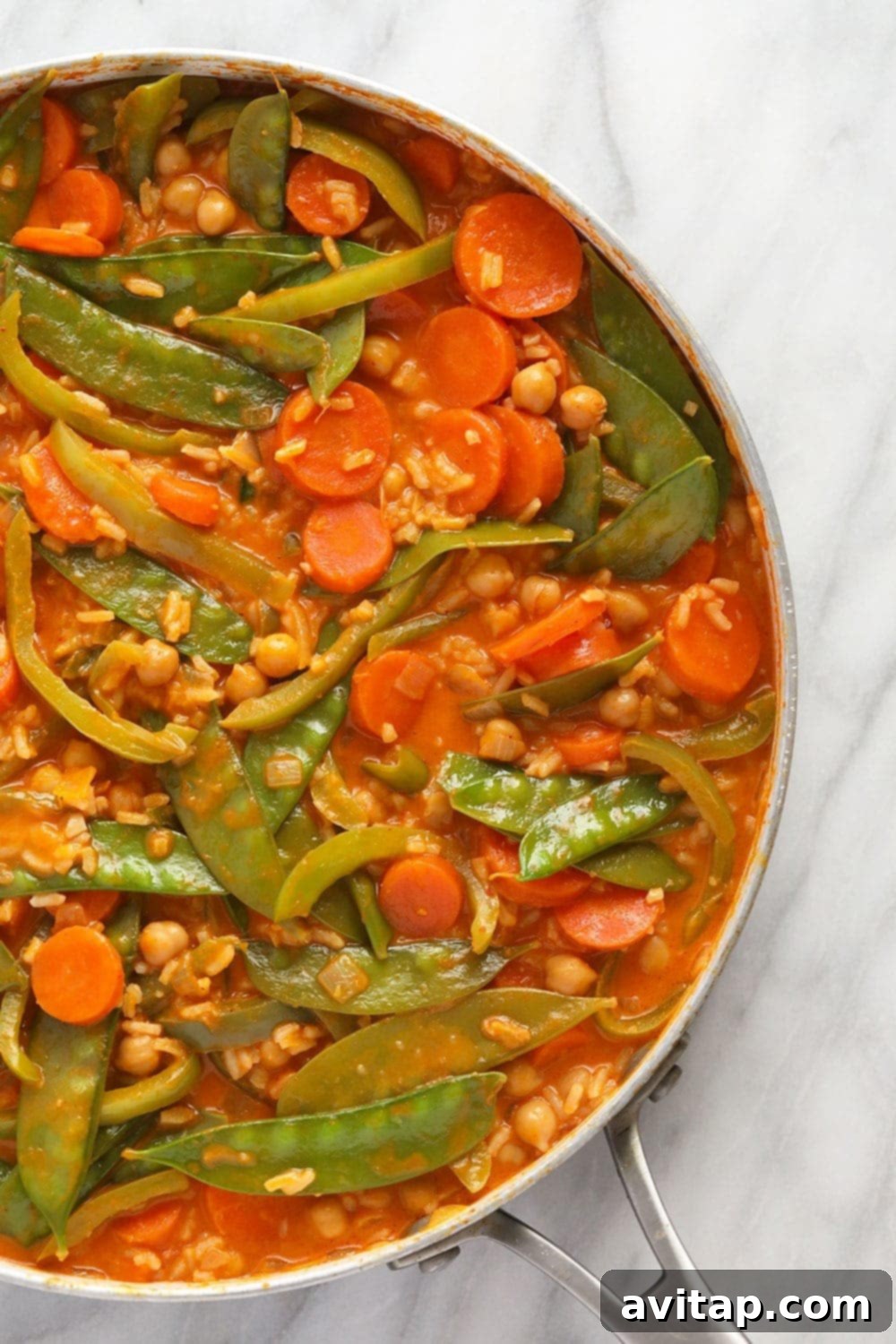 A large skillet filled with vibrant vegetarian Thai curry, ready to be served.