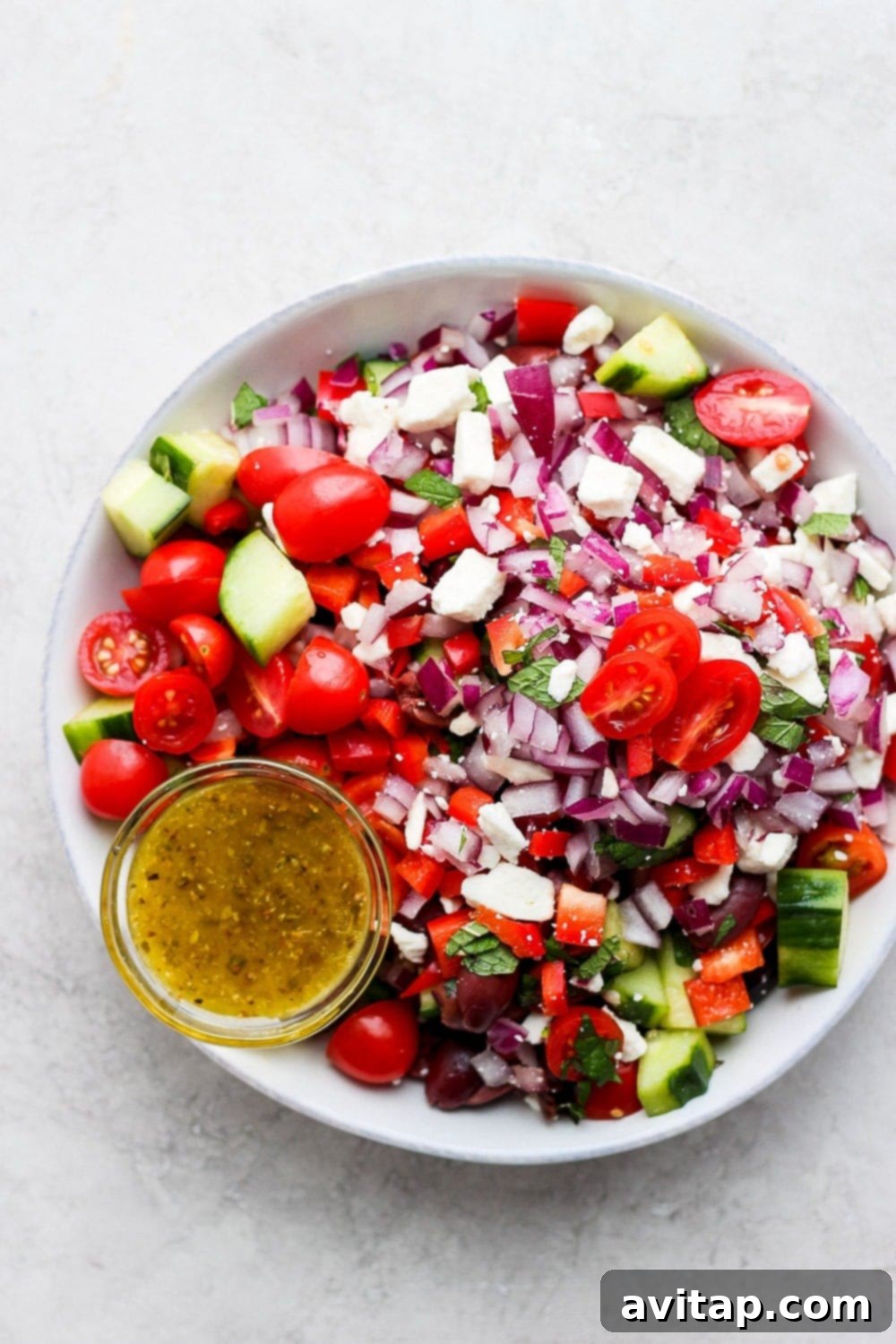 Large bowl of vibrant Greek salad with tomatoes, cucumber, red onion, feta, and olives